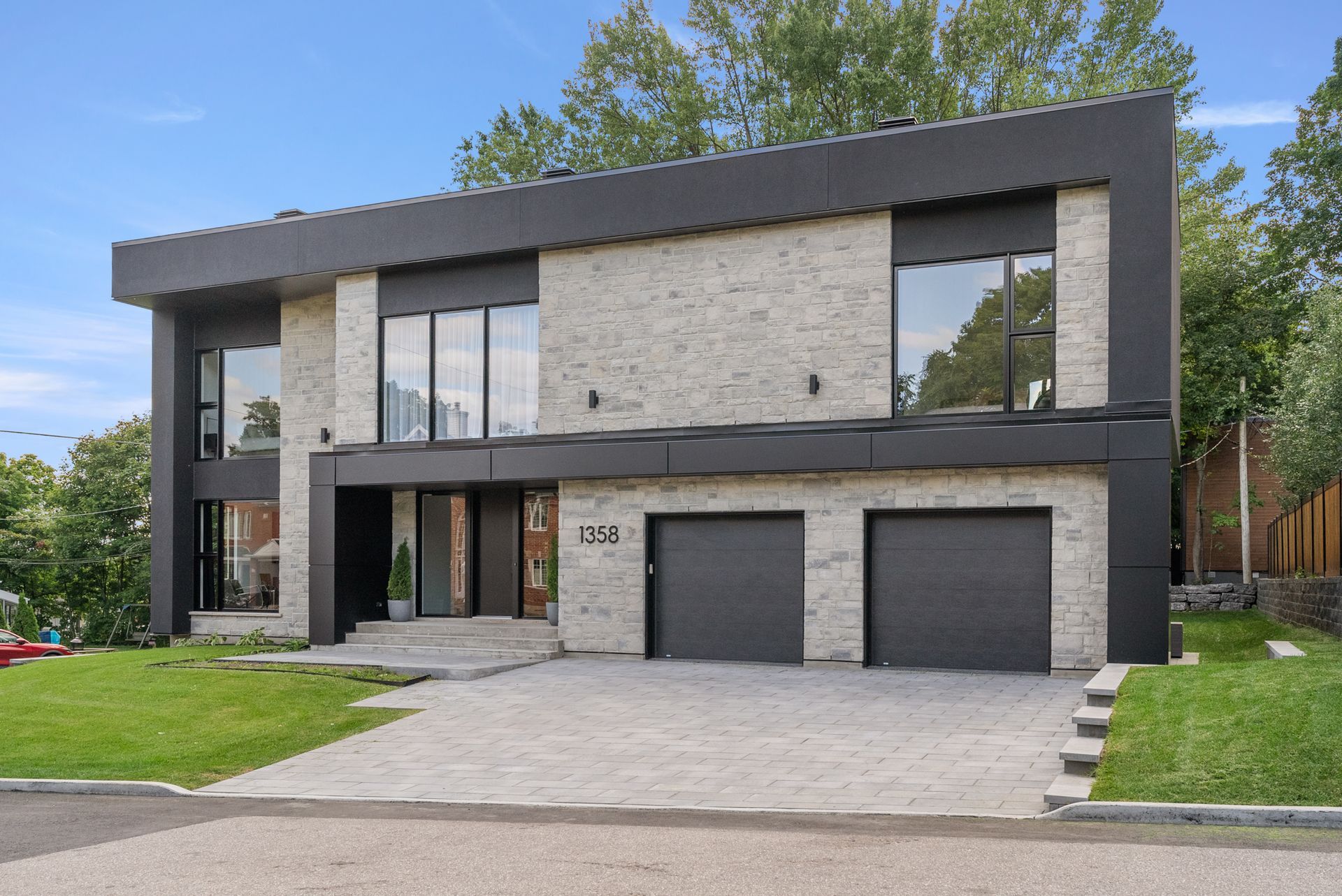 Une grande maison moderne avec deux garages et beaucoup de fenêtres.