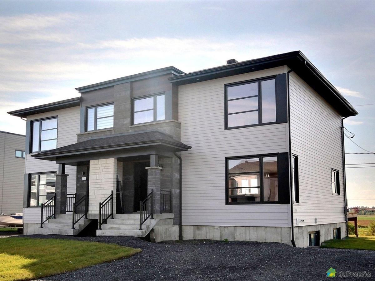 Une grande maison blanche avec beaucoup de fenêtres est à vendre.