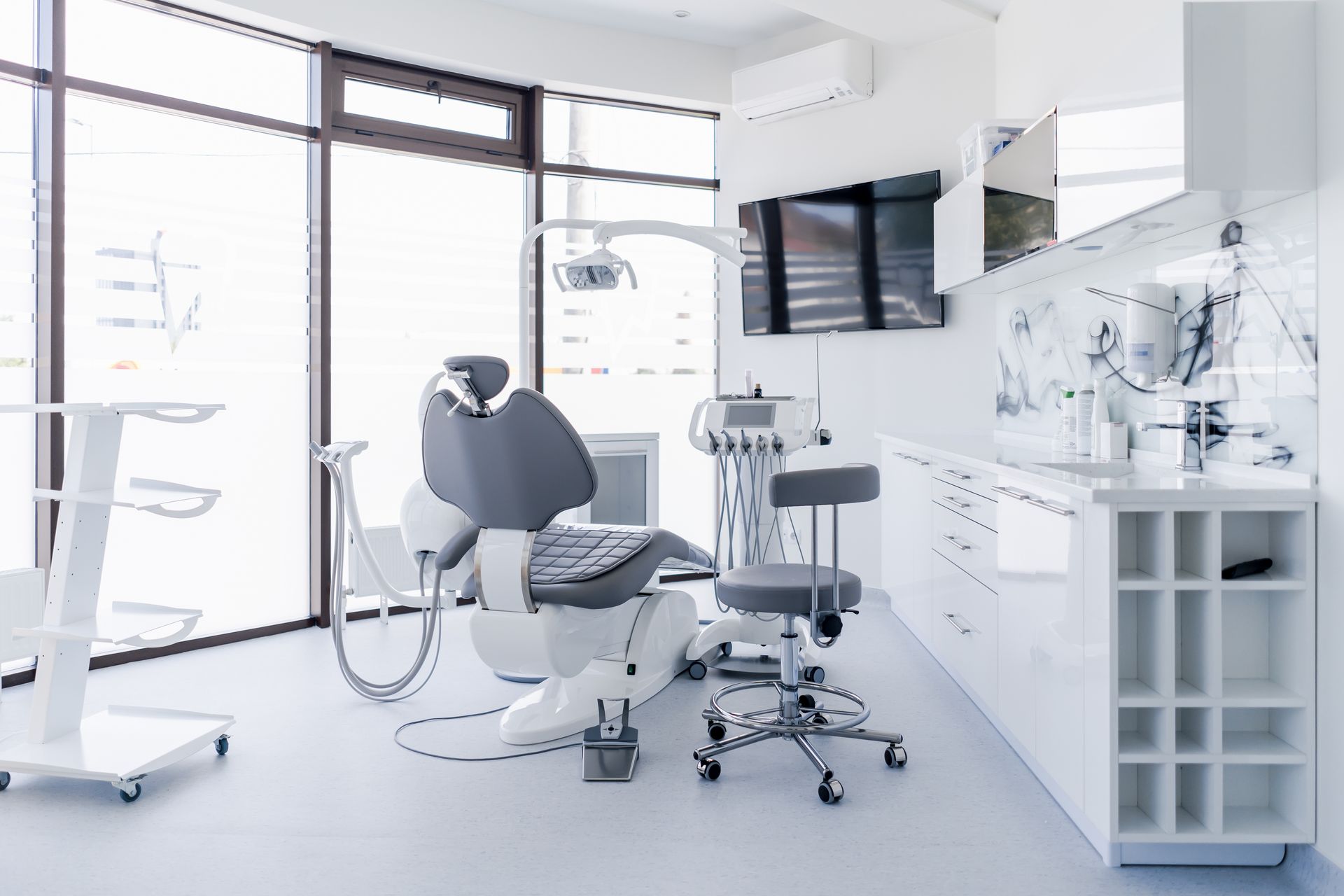 Interior of a dental clinic showing a chair, sink, and dental instruments for patient examinations Interior of a dental clinic showing a chair, sink, and dental instruments for patient examinations