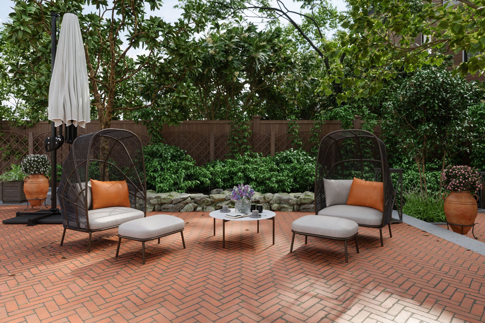 Patio with wicker chairs, ottomans, table, and umbrella on brick, surrounded by greenery.