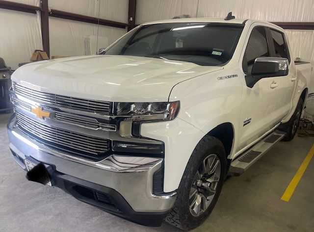 White Chevrolet pickup truck parked indoors in a garage or showroom, front three-quarter view.