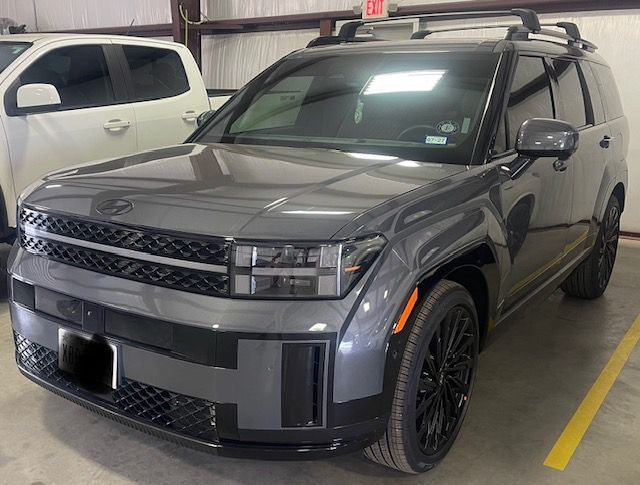 Gray SUV parked indoors in a garage, front three-quarter view with black rims and roof rack