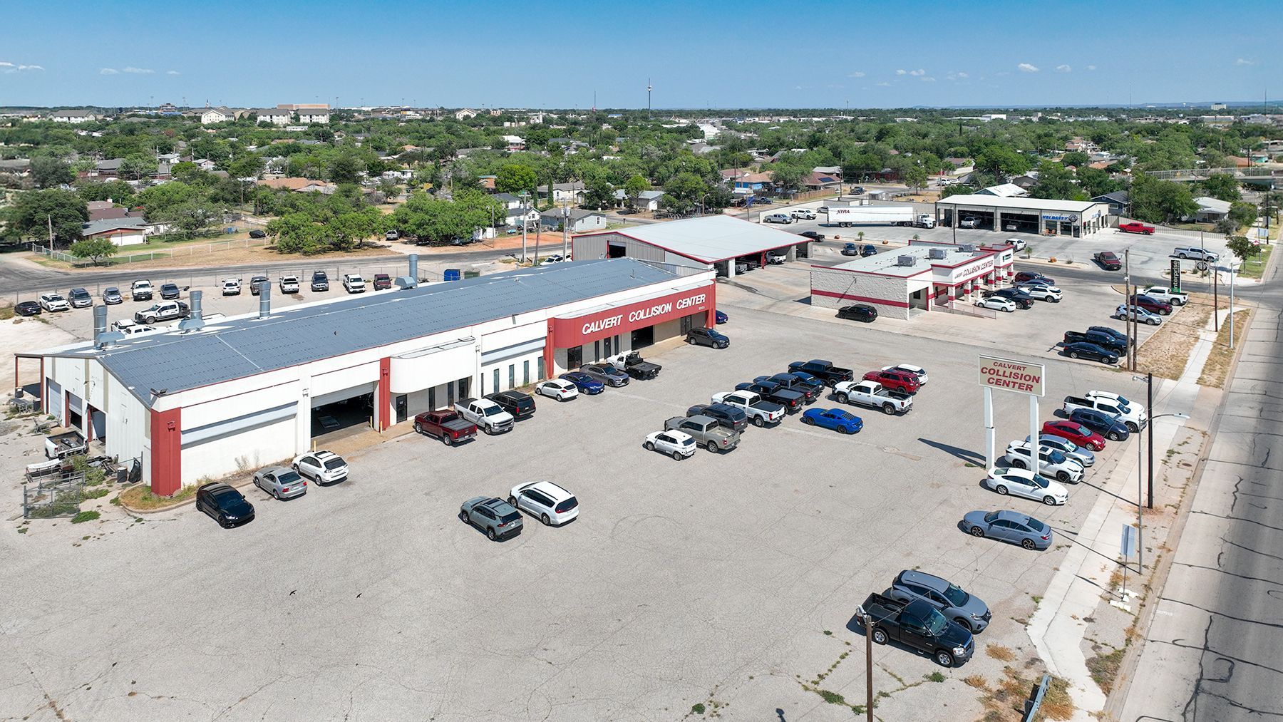Aerial view of a strip mall parking lot with several parked cars and nearby buildings