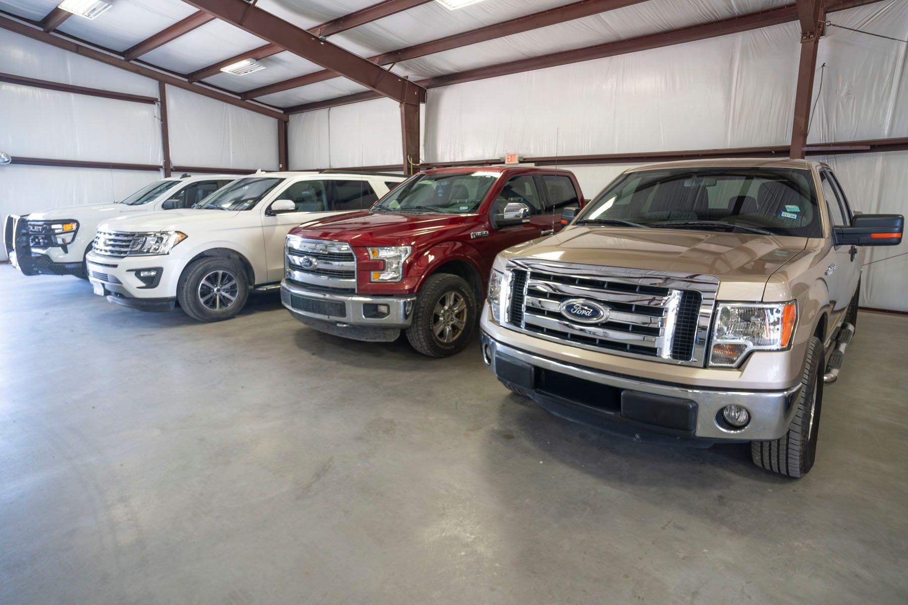 Three pickup trucks parked inside a spacious warehouse garage
