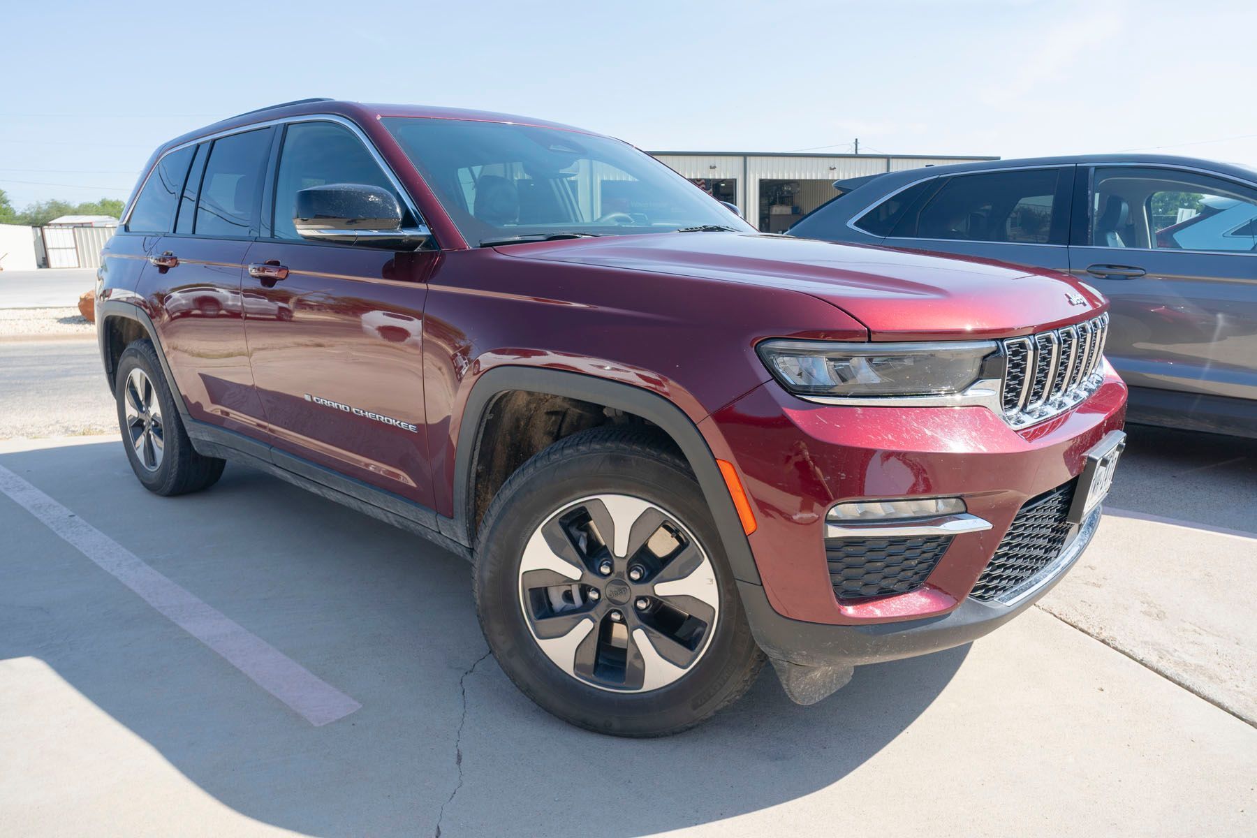 Maroon SUV parked in a lot, front three-quarter view, with a dark car beside it.