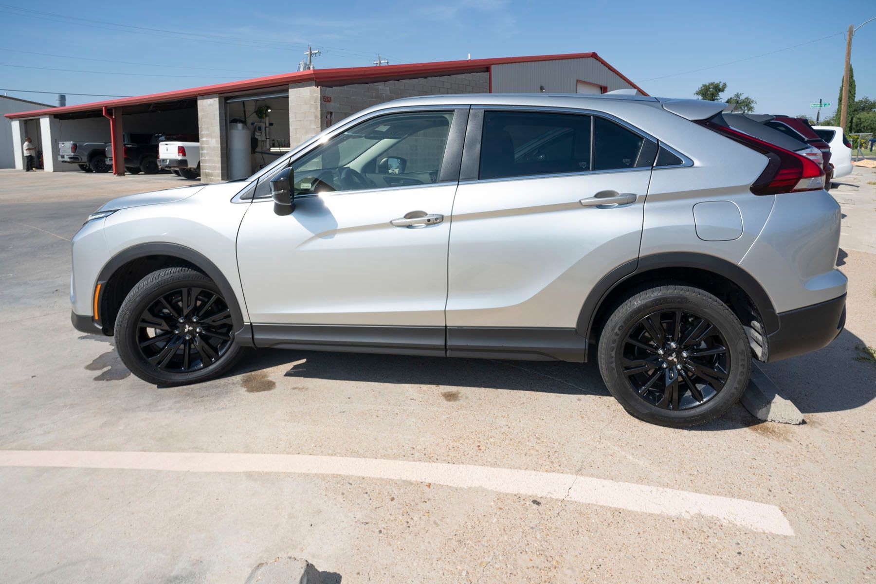 Silver SUV parked in a sunny lot beside a red-roofed building