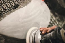 Hand polishing a white ceramic bowl on a potter’s wheel with a cloth