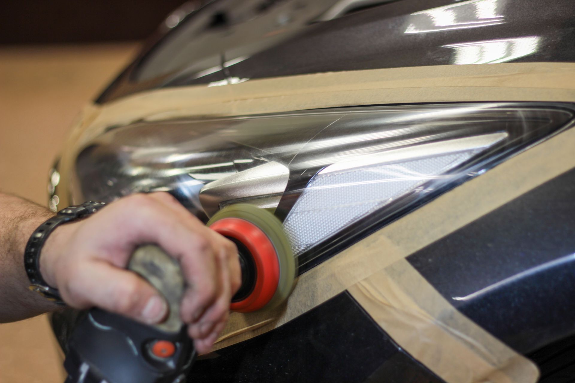 Hand polishing a car headlight with a red buffer pad