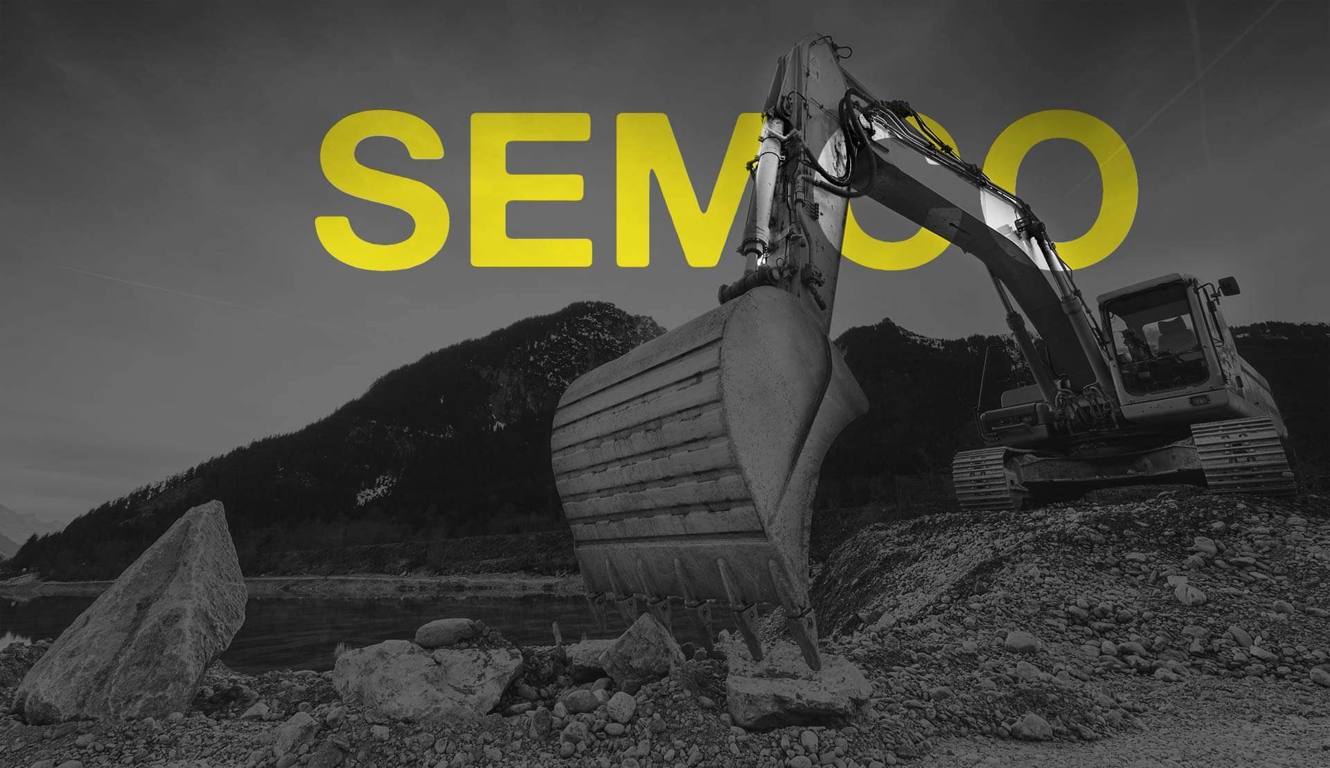Inscription jaune « SEMCO » sur une excavatrice noire et blanche sur un chantier.