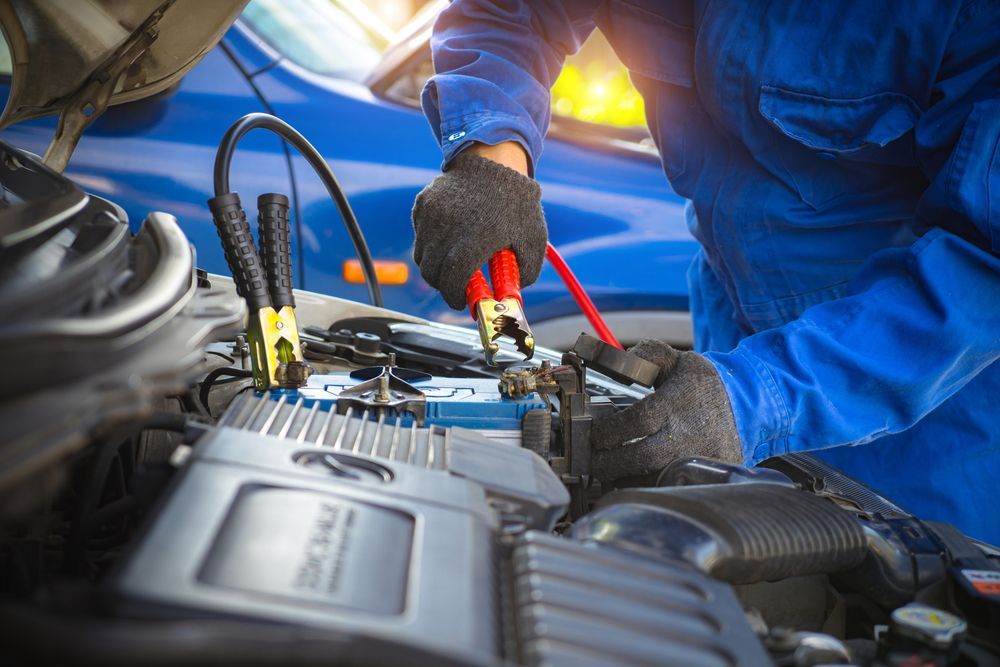 A Man Is Charging a Car Battery with A Jump Starter — Landsborough Mechanical In Landsborough, QLD