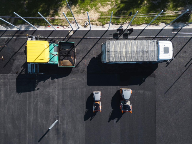 “Overhead view of paving trucks and equipment working on a freshly paved black asphalt surface during an asphalt service in Fulshear, TX”
