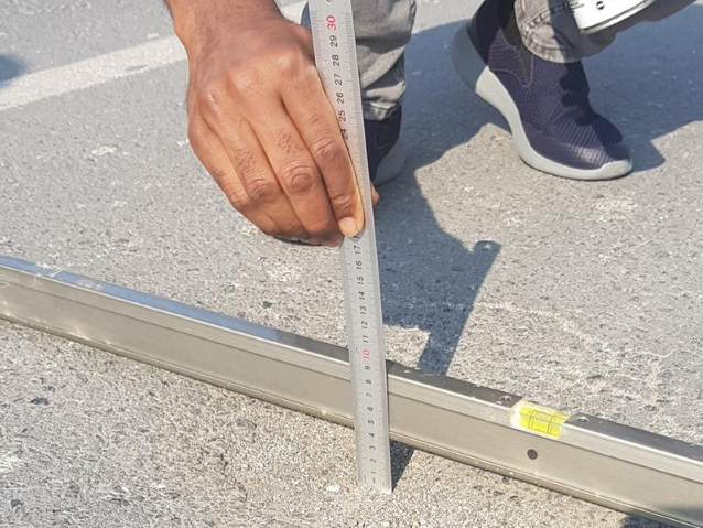 “Worker measuring pavement depth and surface level during asphalt repair preparation for an asphalt service in Fulshear, TX”