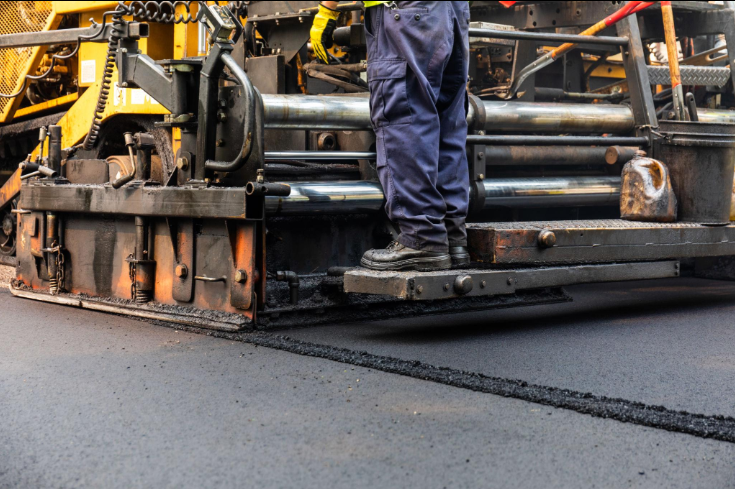 “Close-up of paving equipment smoothing a new asphalt layer with a clean edge during an asphalt service in Fulshear, TX”