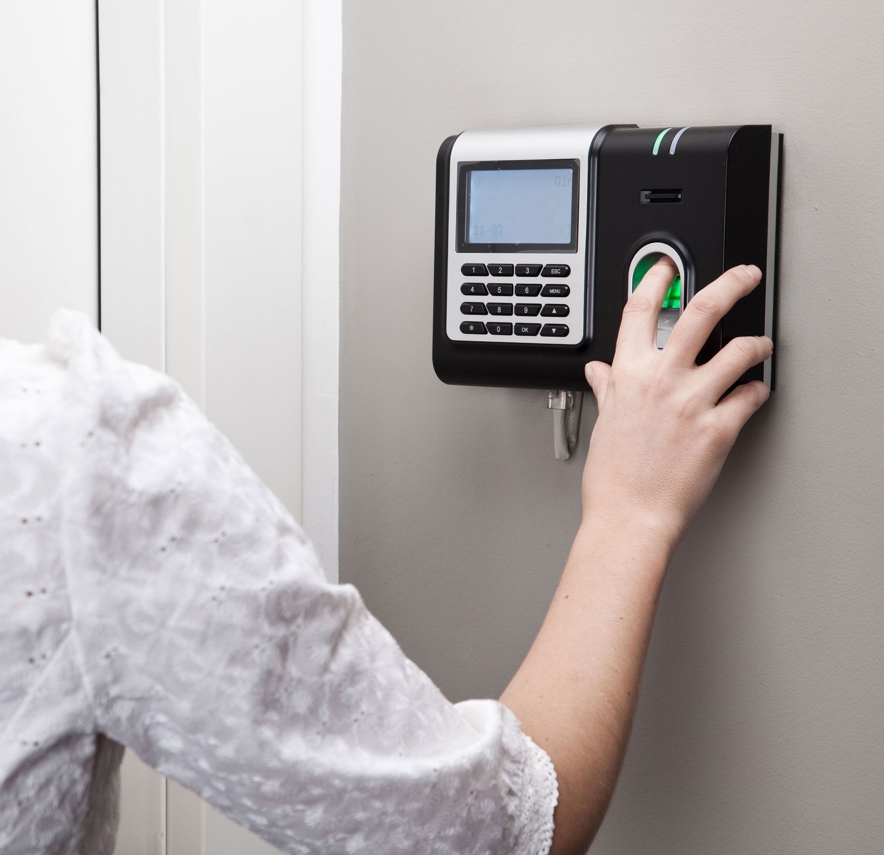 A woman is using a fingerprint scanner on a wall