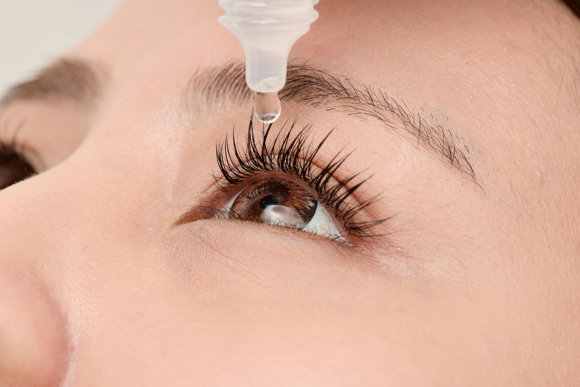 Woman with open eyes and extended eyelashes using eye drops. Woman with open eyes and extended eyelashes using eye drops.