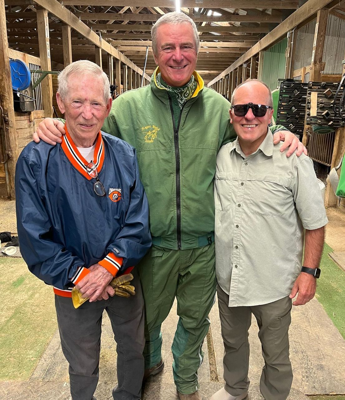 Three men are posing for a picture in a barn.