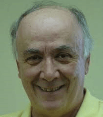 A man with a bald head is smiling and wearing a yellow shirt.