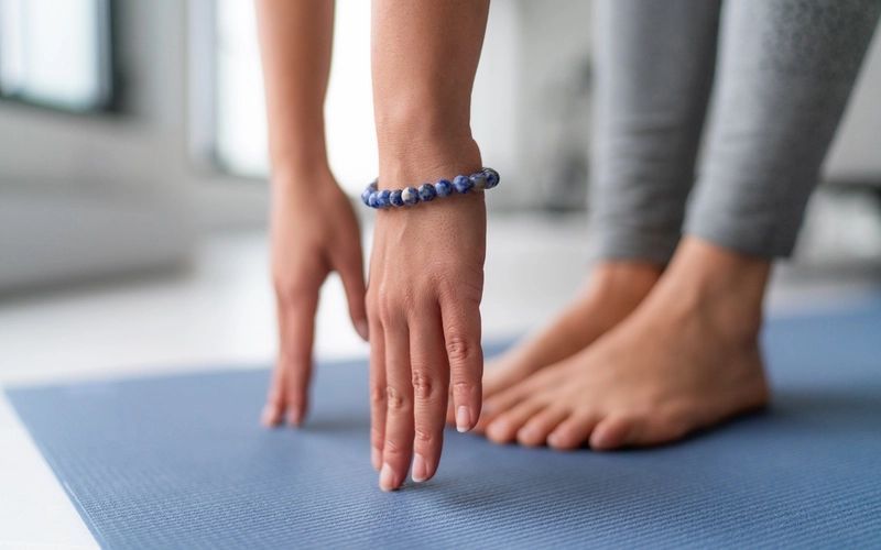A woman wearing a bracelet is standing on a yoga mat.