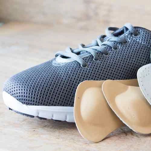 A pair of shoes and insoles on a wooden table.