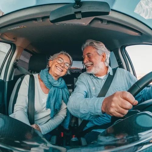A man and a woman are sitting in a car and smiling.