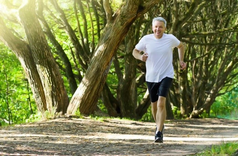 A man is running on a dirt path in the woods.