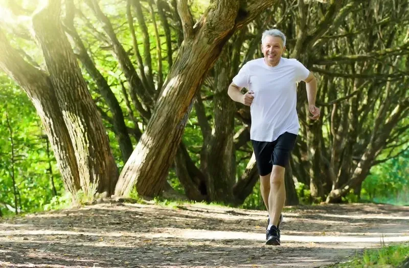 A man is running on a dirt path in the woods.