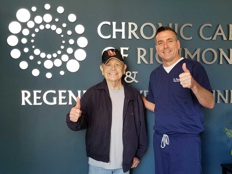 Two men giving a thumbs up in front of a sign that says chronic care