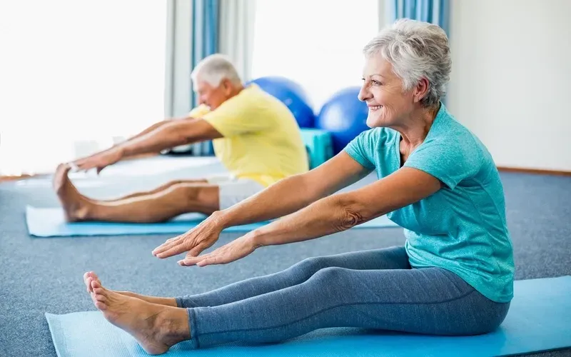 A man and a woman are doing stretching exercises on yoga mats.