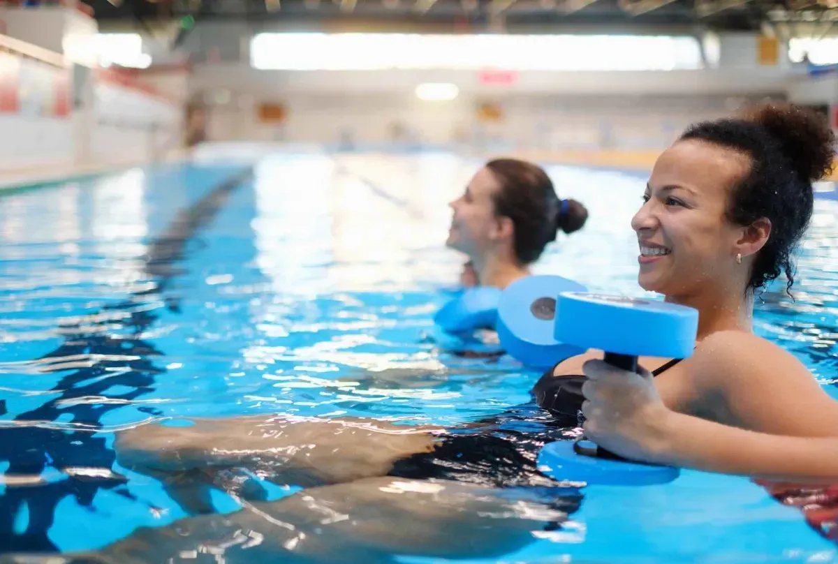 Two women are doing aqua aerobics in a swimming pool.