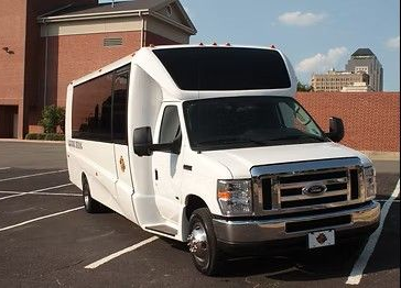 White Ford passenger van in a parking lot, building background.