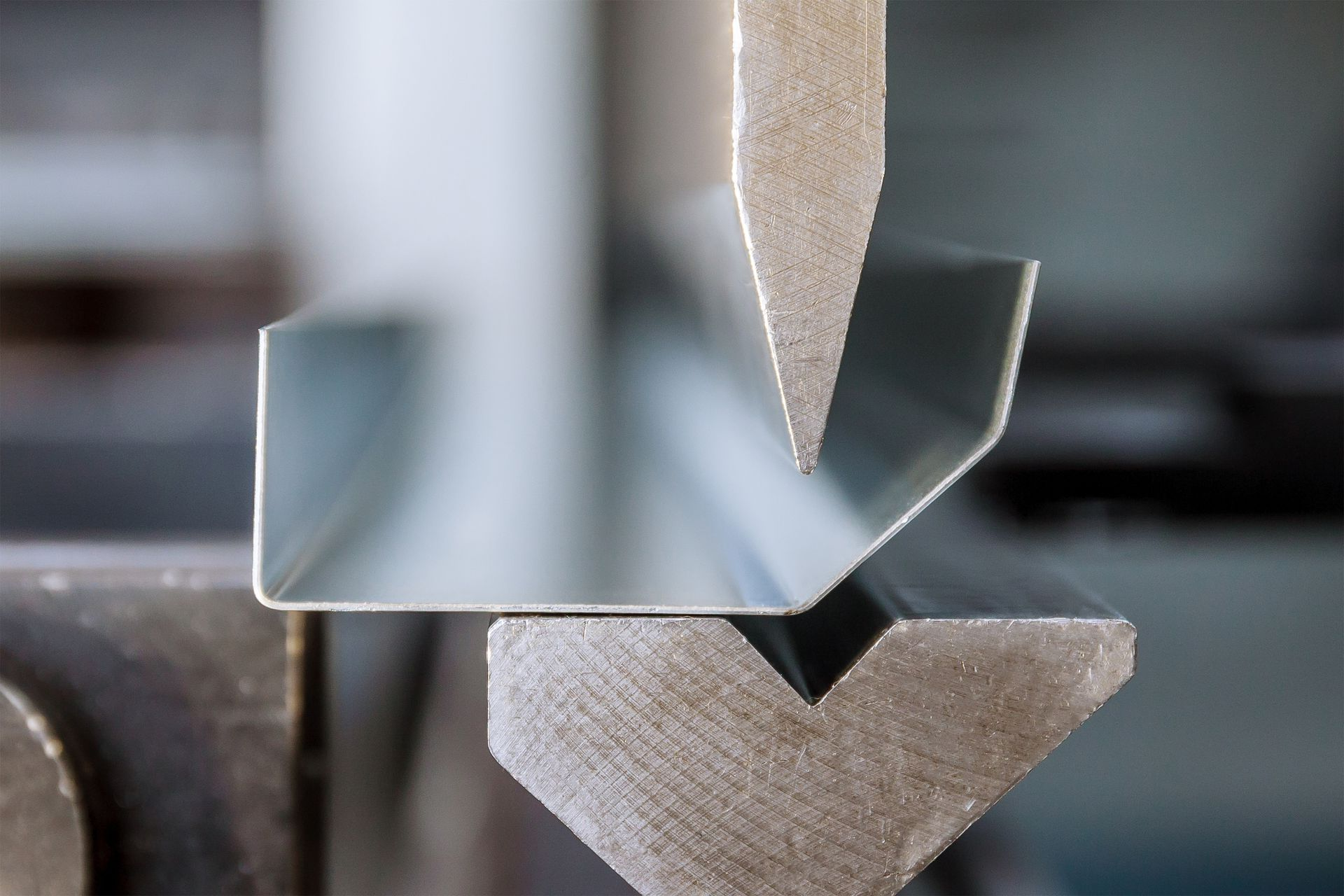 Gros plan sur une presse à métaux pliant une feuille d'argent en forme d'encoche en V.