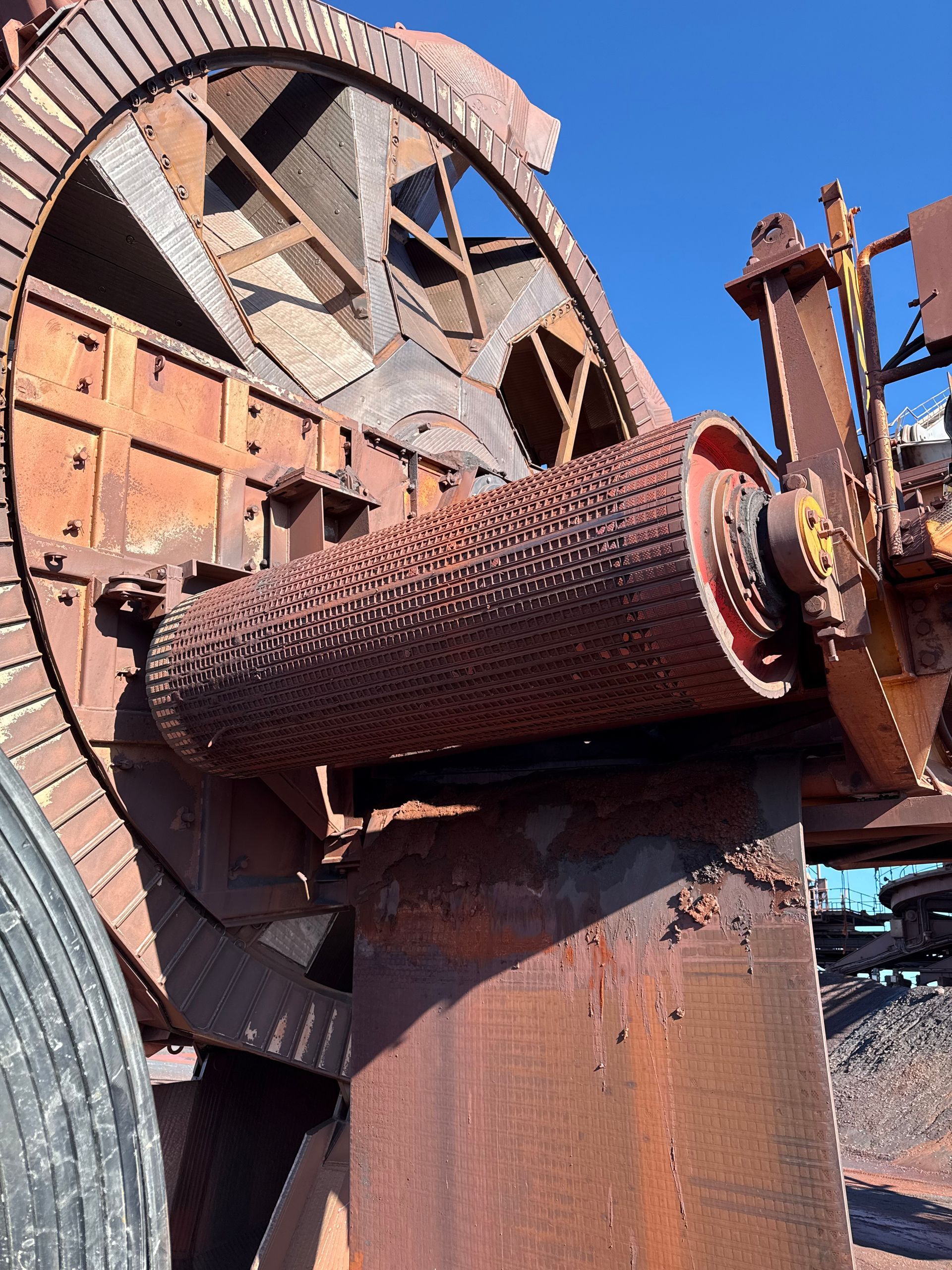 Machines industrielles rouillées avec un grand tambour rotatif et une roue dans une casse à ciel ouvert