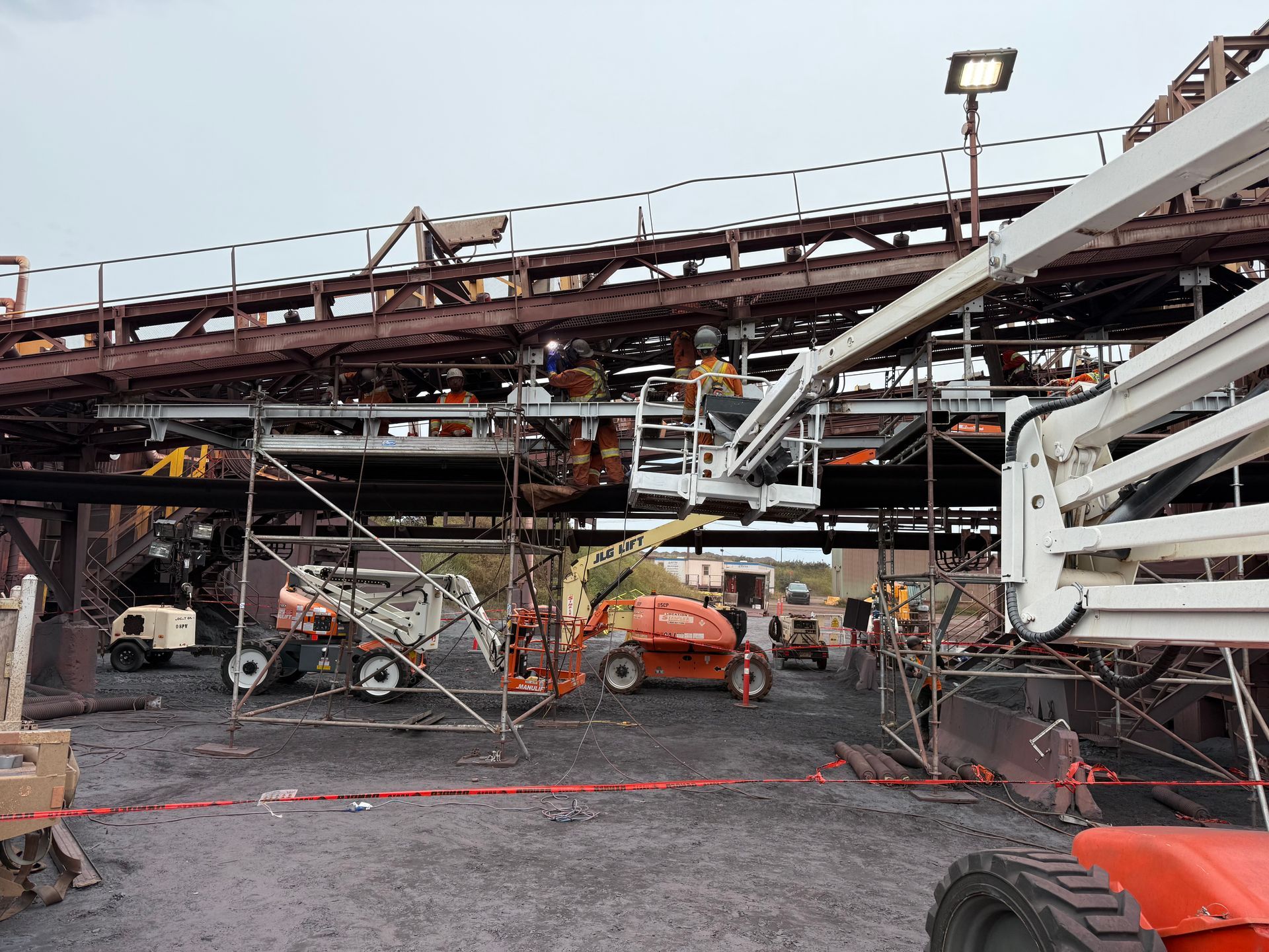Structure industrielle endommagée avec échafaudages effondrés, débris et ruban de signalisation d'urgence sur un chantier