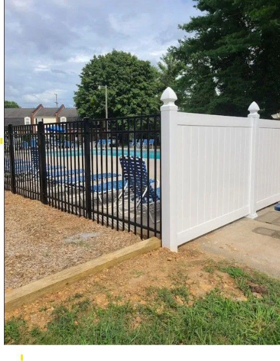 Black aluminum and white vinyl fencing enclosing a community pool area.