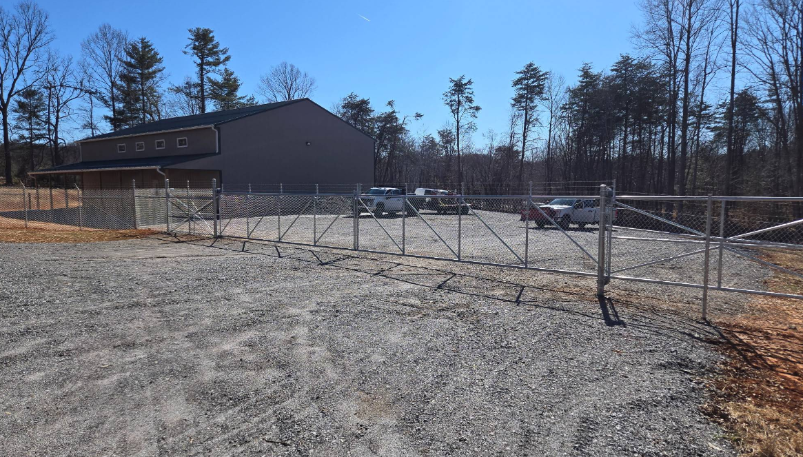 Large chain-link commercial fence with wide gate installed by a Boones Mill commercial fence contractor, securing a business property Large chain-link commercial fence with wide gate installed by a Boones Mill commercial fence contractor, securing a business property