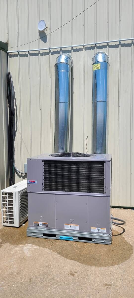 Two blue propane tanks atop a gray outdoor heater beside a beige wall