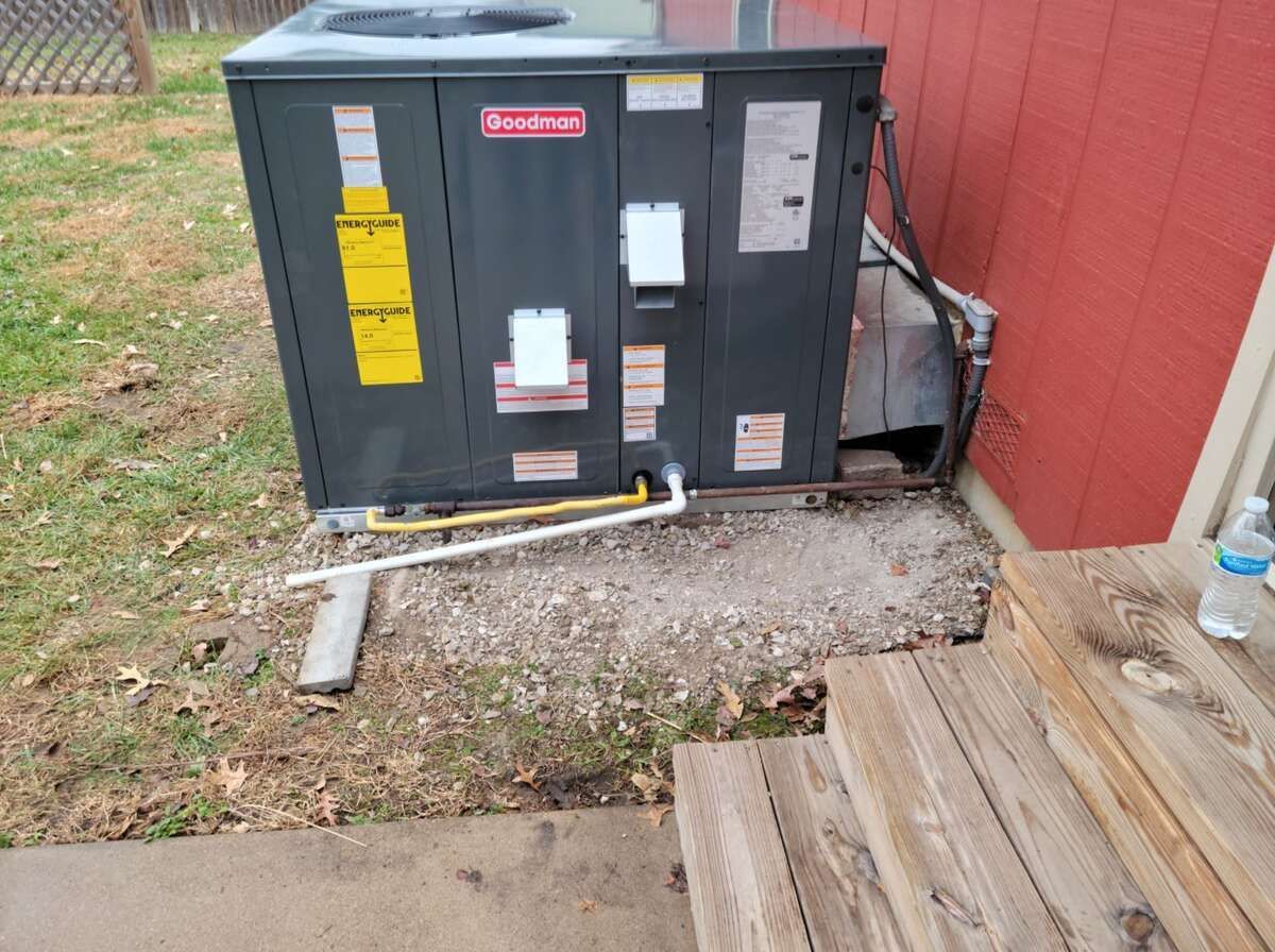 Outdoor HVAC unit beside a red building, with conduit and steps in the foreground.