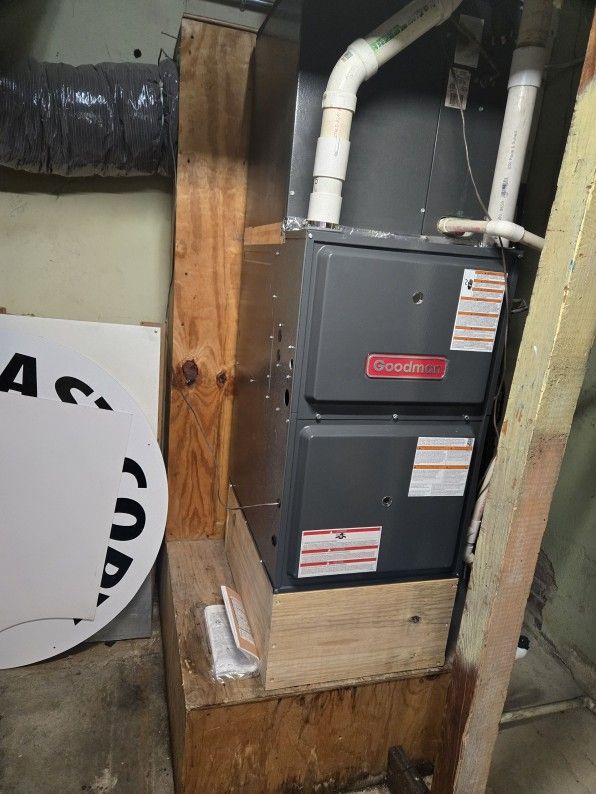 Furnace unit with gray panels and white pipes in a basement utility area.