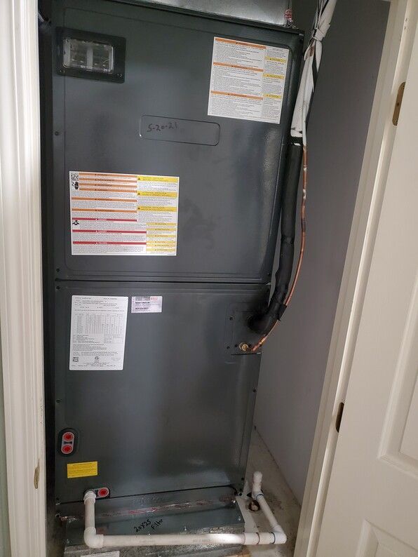 Open HVAC/furnace closet with gray unit, labels, wiring, and white door frame.