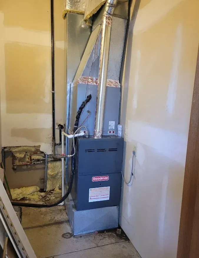 Basement furnace and HVAC ductwork in a utility room with unfinished walls.