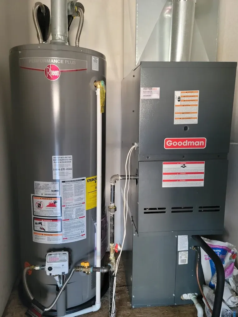 Water heater and Goodman furnace in a utility closet with connected pipes and ductwork