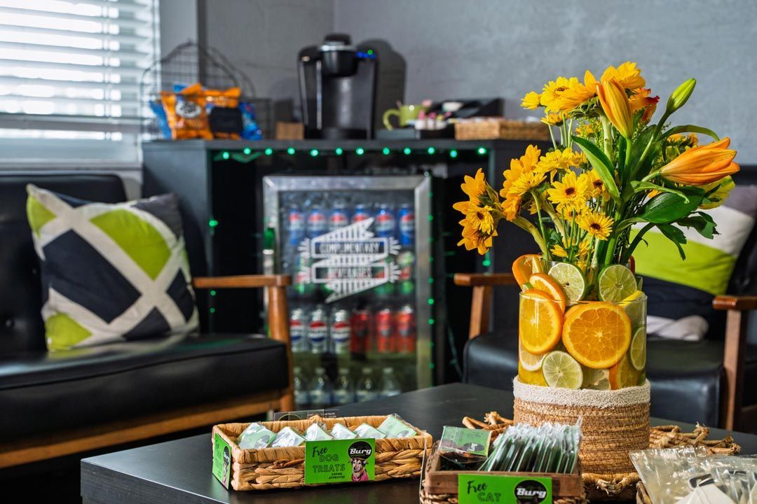 Living room coffee table with flowers, citrus decor, and a small snack tray near a black couch