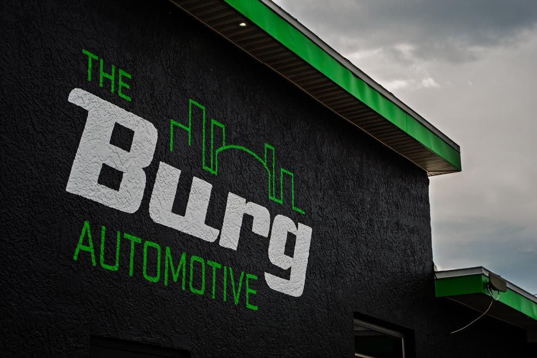Exterior wall sign reading “The Burg Automotive” in green and white on a dark building with green trim.