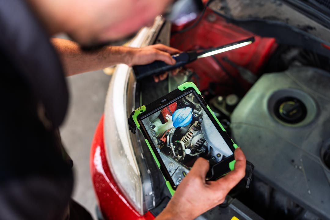 Person using a smartphone to inspect a car engine in the open hood area