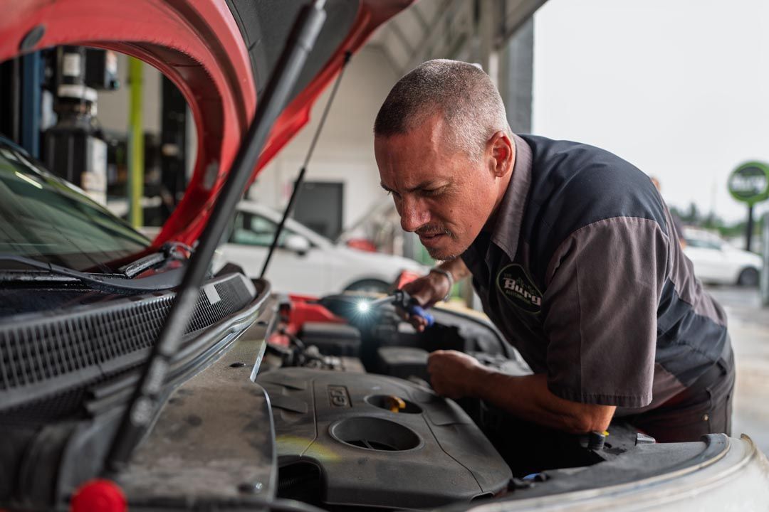 Mechanic inspecting a car engine with the hood open in a service garage