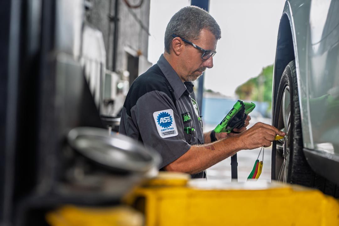 Mechanic inspecting a vehicle with a tablet in a garage, with tools and a lifted car nearby