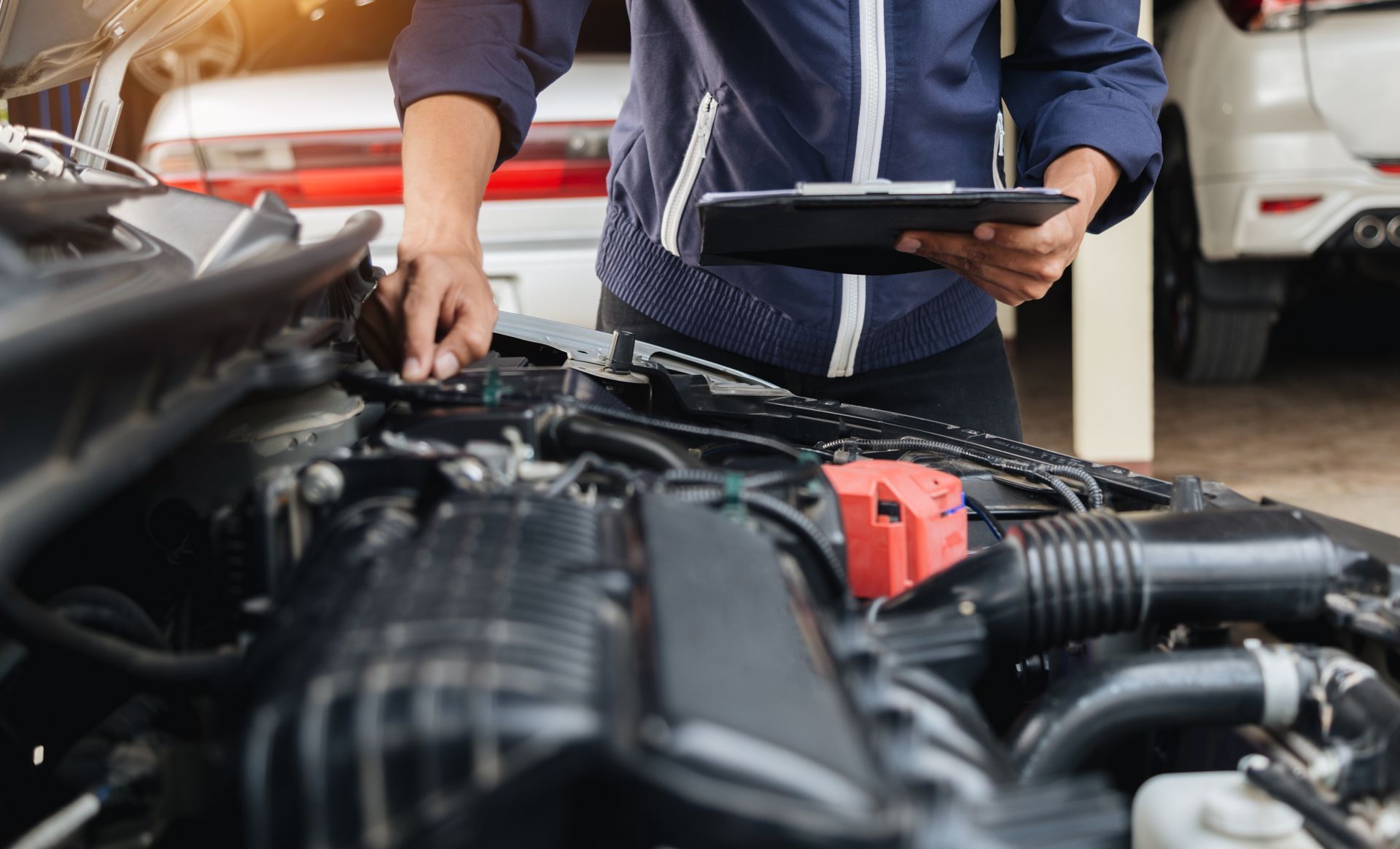 Mechanic inspecting a car engine with a tablet in a garage