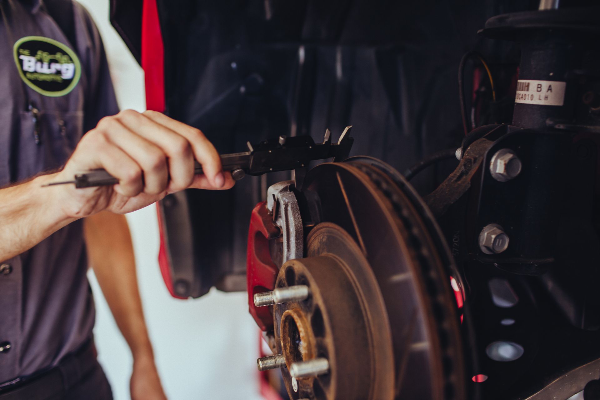 Person using a wrench to adjust a motorcycle brake assembly in a garage