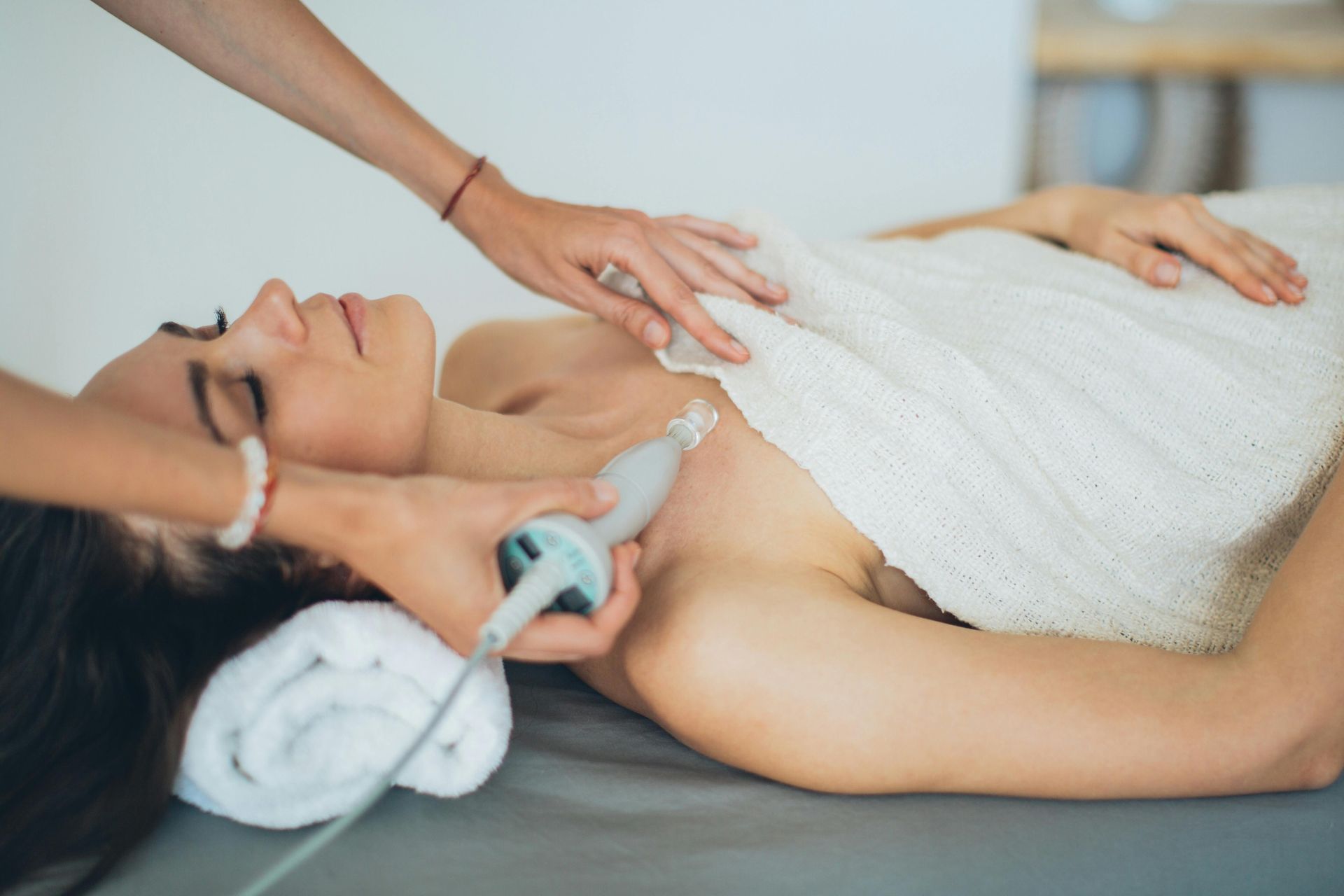 A woman is laying on a bed getting a therapy