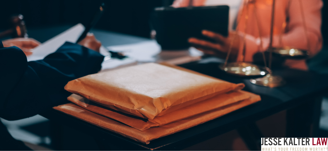 Close-up photograph of orange manila folders and white documents on a dark surface, with blurred background